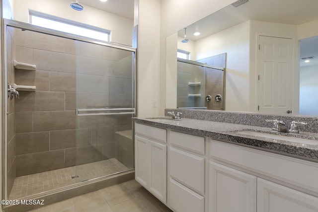 bathroom featuring tile patterned flooring, a shower with shower door, and vanity