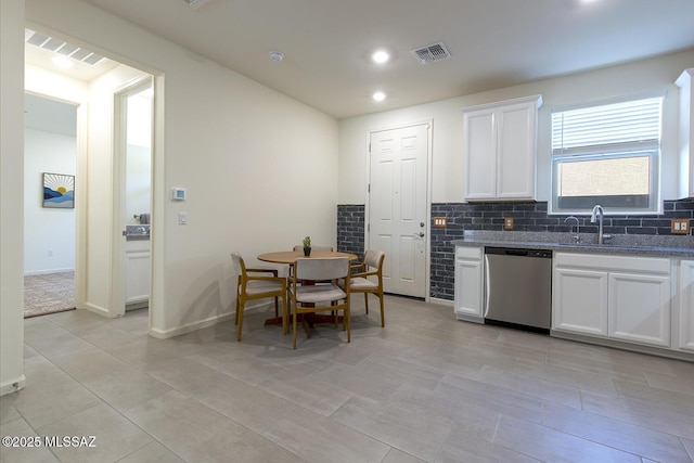 kitchen featuring stainless steel dishwasher, white cabinets, sink, and backsplash