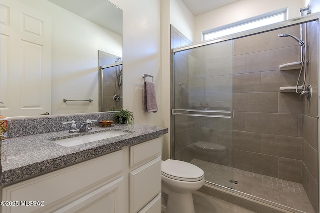 bathroom with a shower with door, vanity, and toilet