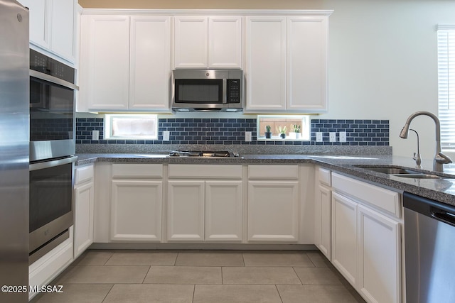 kitchen featuring sink, stainless steel appliances, white cabinetry, and light tile patterned flooring