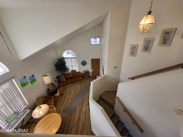 stairs with hardwood / wood-style floors, baseboard heating, and high vaulted ceiling