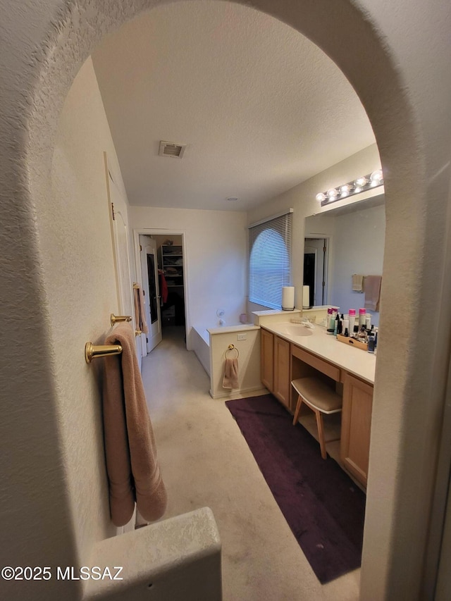 bathroom with vanity, a bathtub, and a textured ceiling