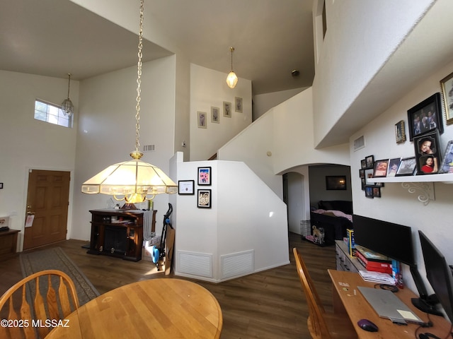 dining room featuring a notable chandelier, a towering ceiling, and dark wood-type flooring