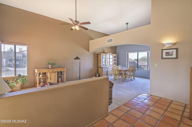 carpeted living room with high vaulted ceiling and ceiling fan