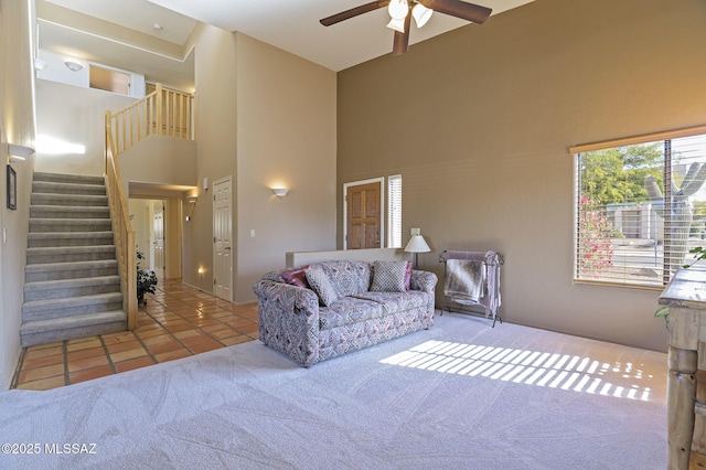 carpeted living room featuring a towering ceiling and ceiling fan