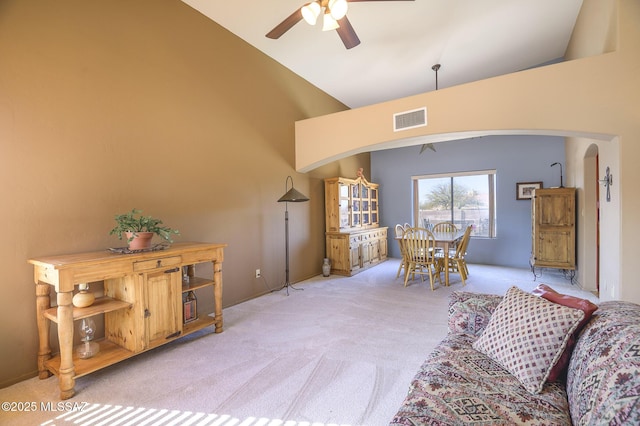 interior space featuring ceiling fan, high vaulted ceiling, and light carpet