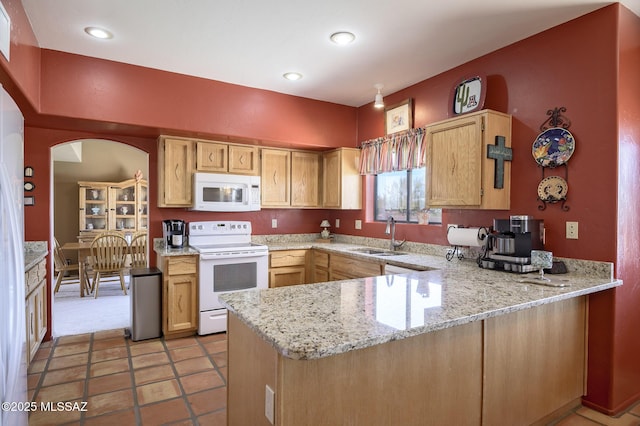 kitchen with sink, light stone counters, white appliances, and kitchen peninsula