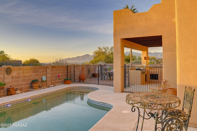 pool at dusk featuring a mountain view and a patio area