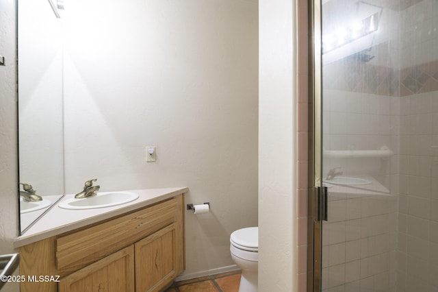 bathroom featuring tile patterned floors, vanity, toilet, and a shower with shower door