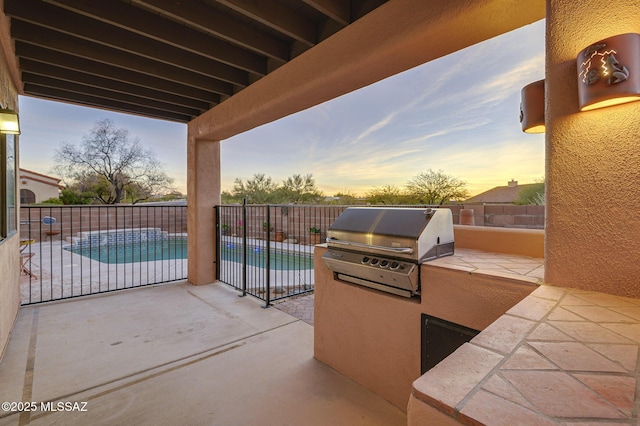 patio terrace at dusk featuring a fenced in pool, a grill, and area for grilling