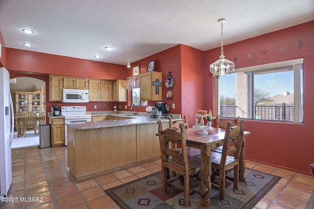 kitchen featuring white appliances, decorative light fixtures, a chandelier, and a wealth of natural light