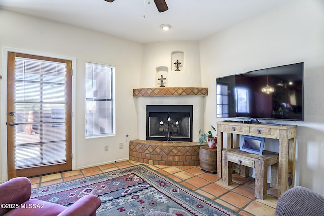 living room featuring ceiling fan, a large fireplace, and tile patterned flooring