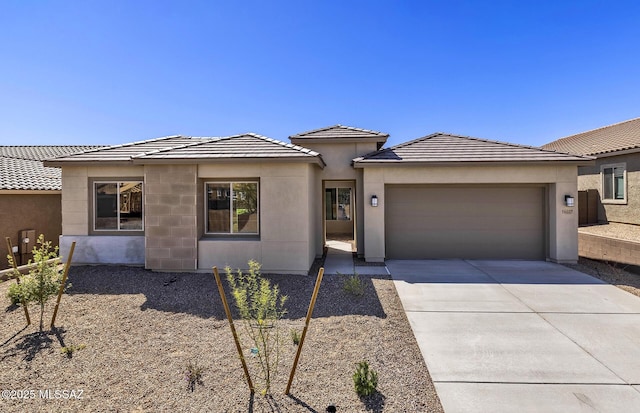prairie-style house featuring a tile roof, an attached garage, driveway, and stucco siding