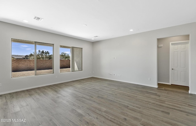 empty room with wood finished floors, baseboards, visible vents, and recessed lighting