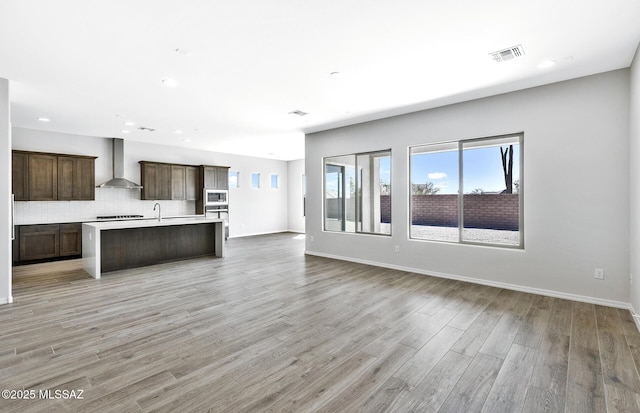 unfurnished living room with light wood-style floors, a healthy amount of sunlight, a sink, and recessed lighting