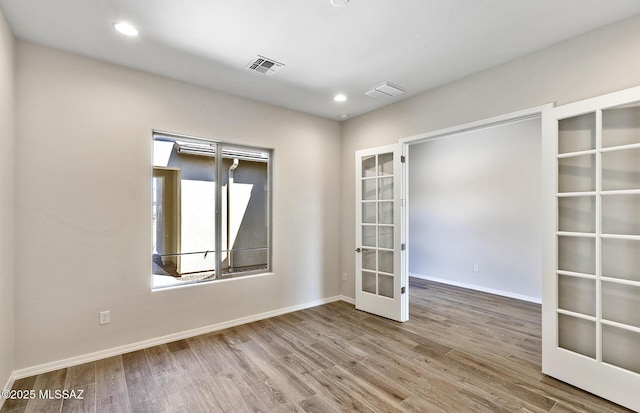 empty room featuring visible vents, baseboards, recessed lighting, wood finished floors, and french doors