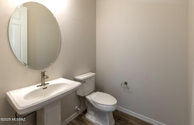 bathroom featuring toilet, wood finished floors, a sink, and baseboards