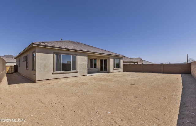 back of house with a tiled roof, a fenced backyard, and stucco siding