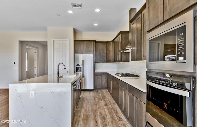 kitchen with light wood-style floors, a sink, visible vents, and stainless steel appliances
