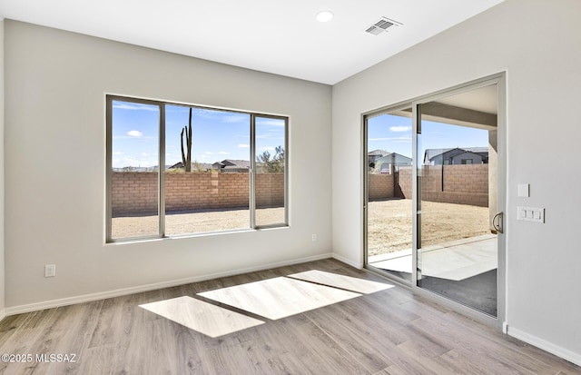 unfurnished room with visible vents, baseboards, plenty of natural light, and wood finished floors