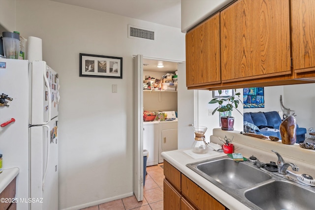 kitchen with washer / dryer, white refrigerator, light tile patterned floors, and sink