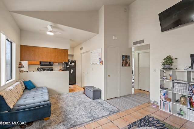 tiled living room featuring ceiling fan and high vaulted ceiling