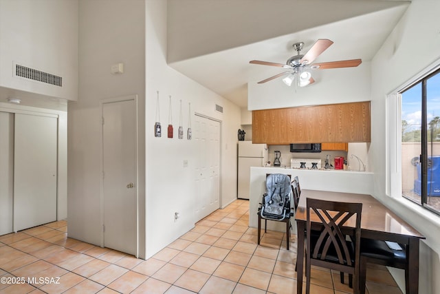 kitchen featuring white refrigerator, light tile patterned flooring, ceiling fan, and kitchen peninsula