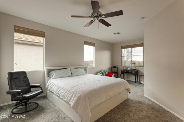 carpeted bedroom featuring multiple windows and ceiling fan