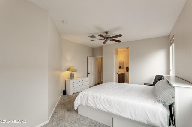 carpeted bedroom with ensuite bath and ceiling fan