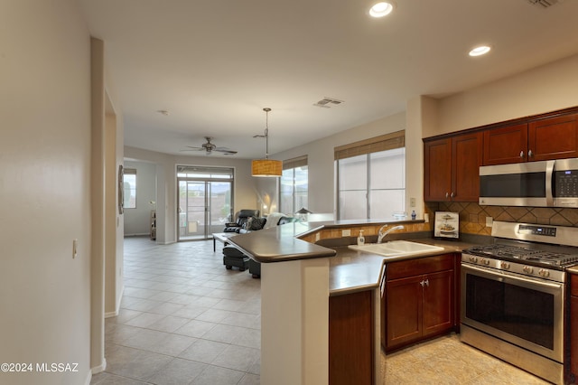 kitchen featuring kitchen peninsula, stainless steel appliances, ceiling fan, sink, and hanging light fixtures