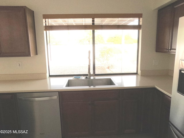 kitchen featuring a wealth of natural light, sink, stainless steel dishwasher, and dark brown cabinets