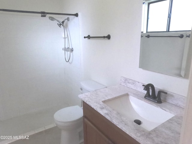 bathroom with tile patterned floors, vanity, toilet, and a tile shower