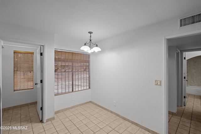 spare room featuring light tile patterned flooring and a chandelier