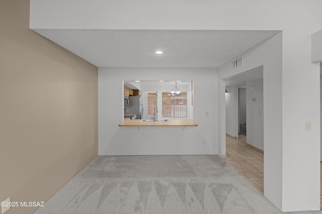 unfurnished living room featuring sink and light carpet