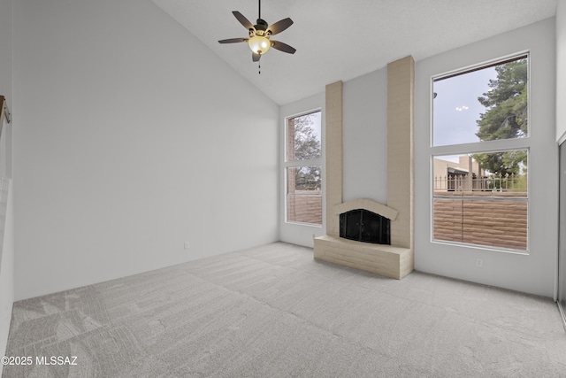 unfurnished living room featuring high vaulted ceiling, a brick fireplace, ceiling fan, and light colored carpet