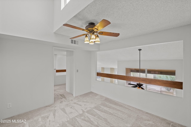 unfurnished room featuring light carpet, a textured ceiling, and ceiling fan