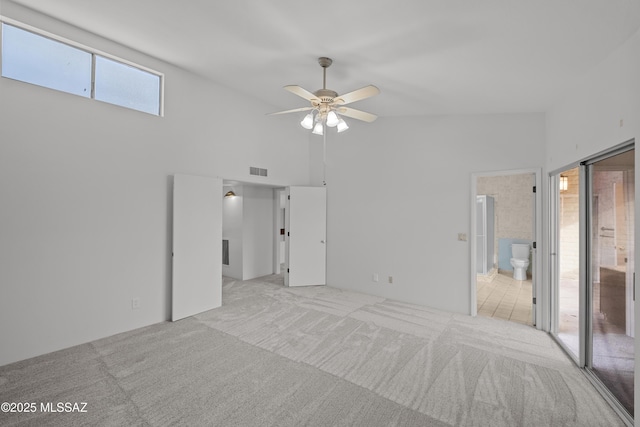 unfurnished bedroom with light carpet, connected bathroom, high vaulted ceiling, and ceiling fan