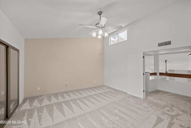 unfurnished bedroom featuring a closet, light colored carpet, and ceiling fan