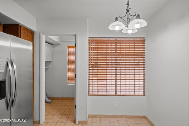 kitchen with stainless steel refrigerator with ice dispenser, light tile patterned floors, pendant lighting, and a notable chandelier