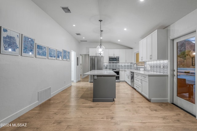 kitchen with pendant lighting, a center island, backsplash, white cabinetry, and stainless steel appliances