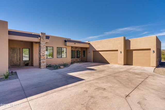 adobe home with concrete driveway, stucco siding, and a garage