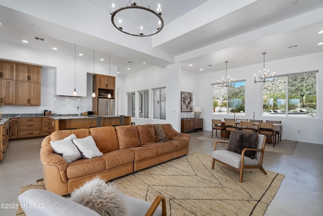 living room featuring a chandelier, finished concrete flooring, a towering ceiling, and recessed lighting