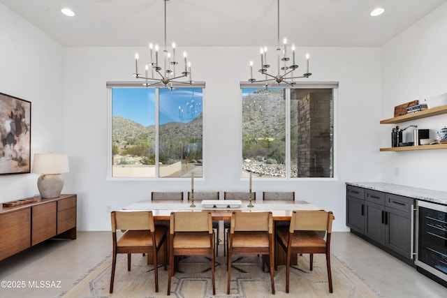 dining area featuring beverage cooler, a chandelier, concrete flooring, recessed lighting, and a mountain view