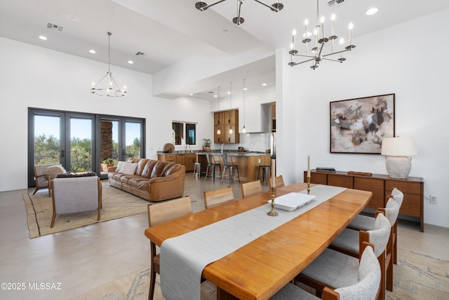 dining space featuring a chandelier, concrete flooring, a high ceiling, and recessed lighting