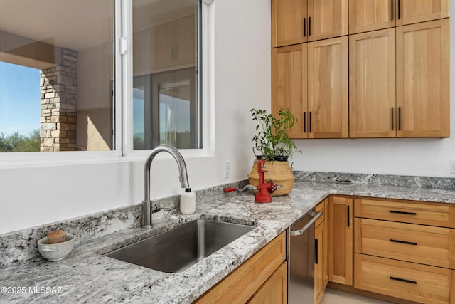 kitchen with a sink, dishwasher, and light stone counters