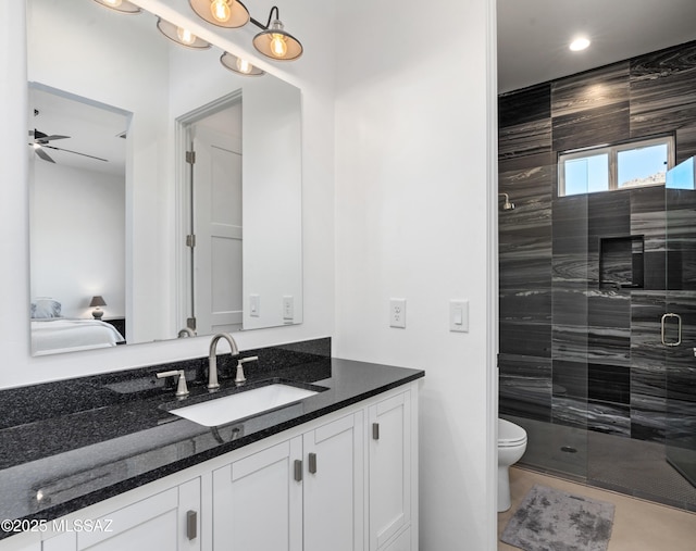 ensuite bathroom featuring ceiling fan, a shower stall, toilet, and vanity