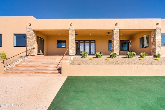rear view of house featuring stucco siding and french doors