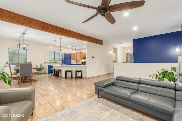 living room featuring beamed ceiling and ceiling fan with notable chandelier