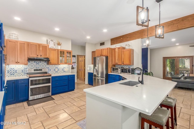 kitchen with decorative backsplash, appliances with stainless steel finishes, a kitchen bar, sink, and hanging light fixtures