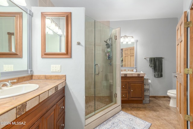 bathroom featuring toilet, vanity, tile patterned floors, and an enclosed shower